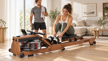 A couple sharing a sleek black Wenoker RW10 water rowing machine in a modern sunlit living room, with one partner comfortably cinching the footboard straps.